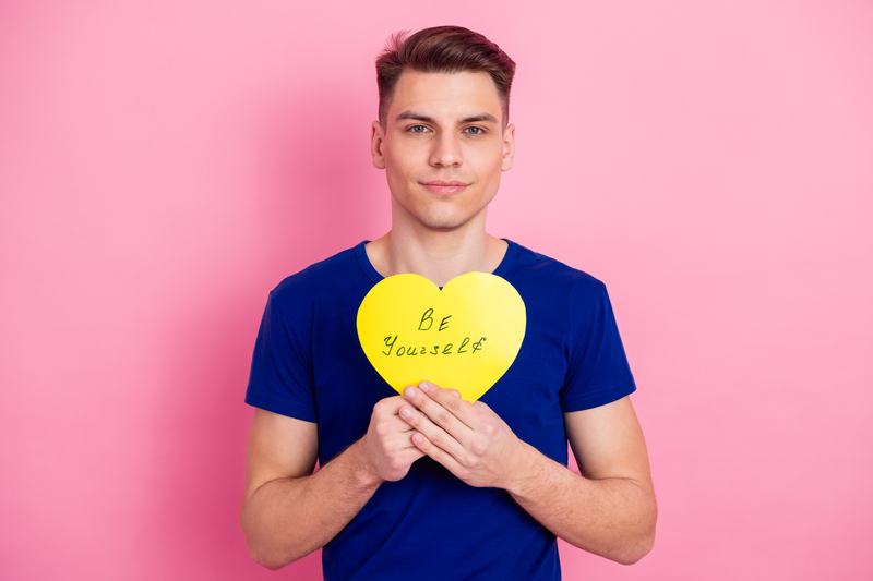 Teenage Boy Holding A Heart Shaped Sign That Reads be Yourself