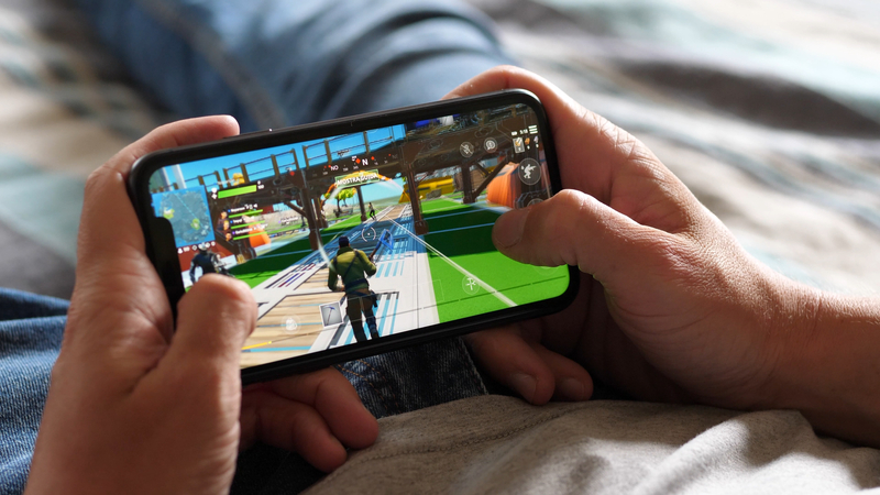 Young Man Gaming On Mobile Phone Screen