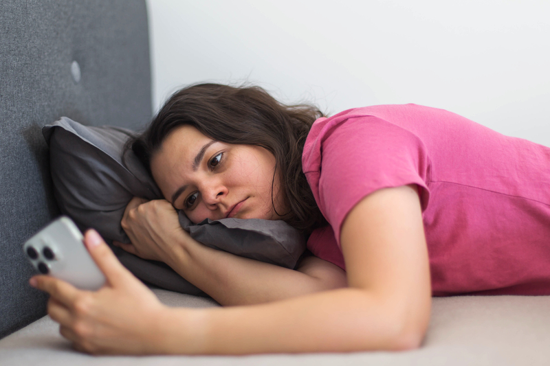 Young Teenage Girl Looking At Phone Looking Fed Up With Social Comparison
