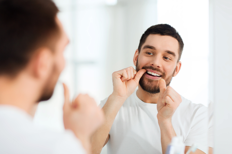 Young Man Flossing Teeth As Part Of His Small Grooming Routine